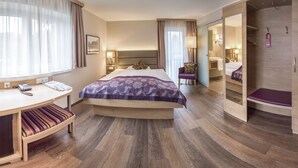 A hotel room with a bed, bedside table, chair, desk, and a mirror.