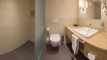 A modern bathroom with a shower, toilet, sink, and mirror.