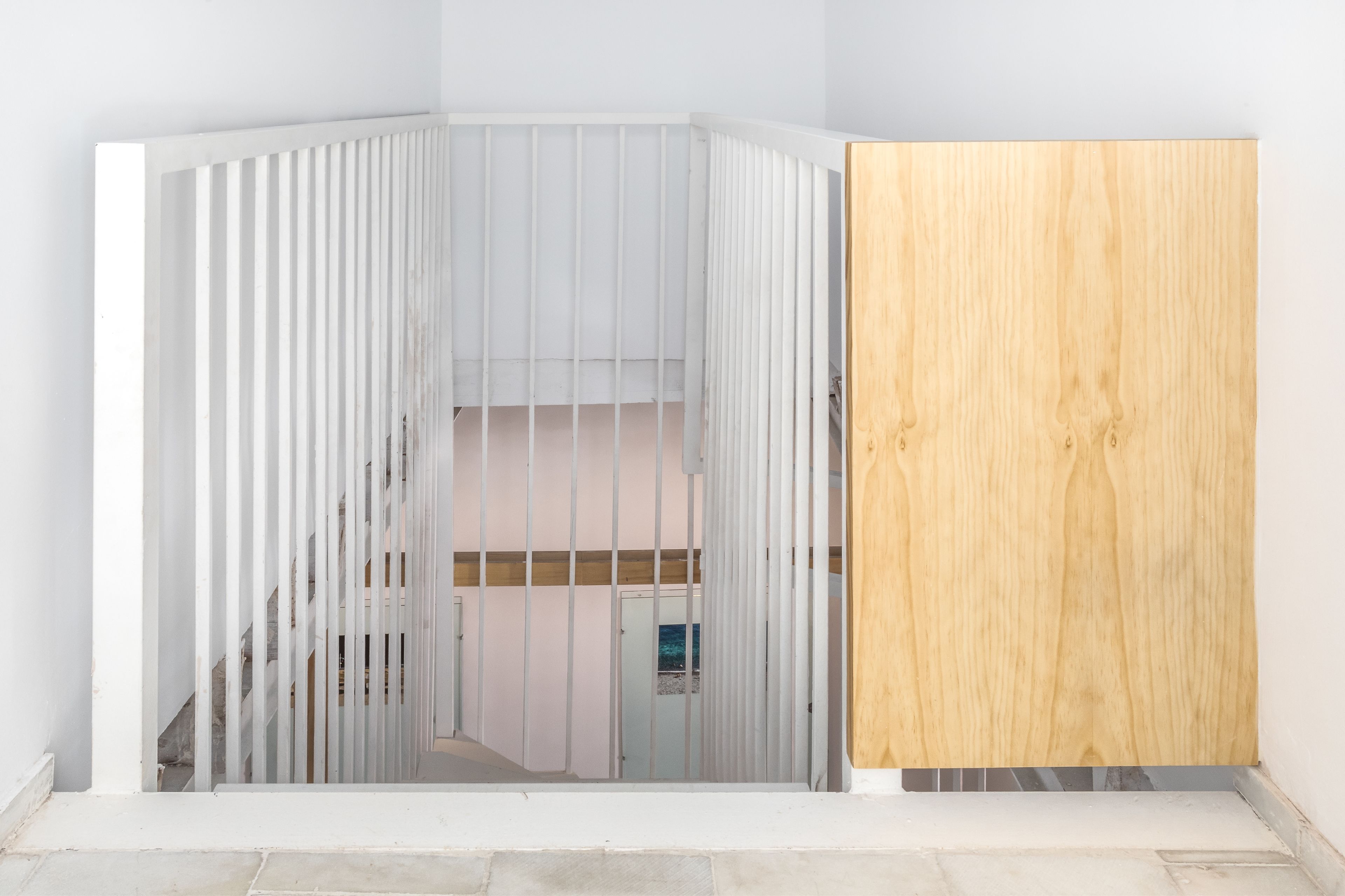 A corner of a room with a white partition and a wooden panel.