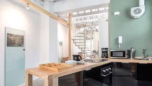 Cozinha moderna com mesa de madeira, eletrodomésticos pretos e parede verde.