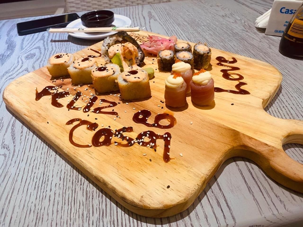 A wooden serving board with sushi and a handwritten message.