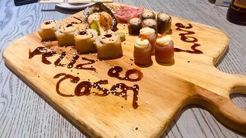 A wooden serving board with sushi and a handwritten message.