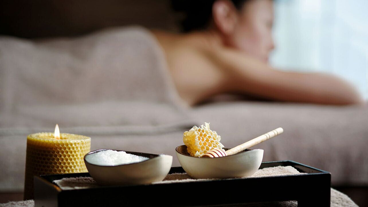 A spa setting with a candle, honeycomb, and bowls on a tray.