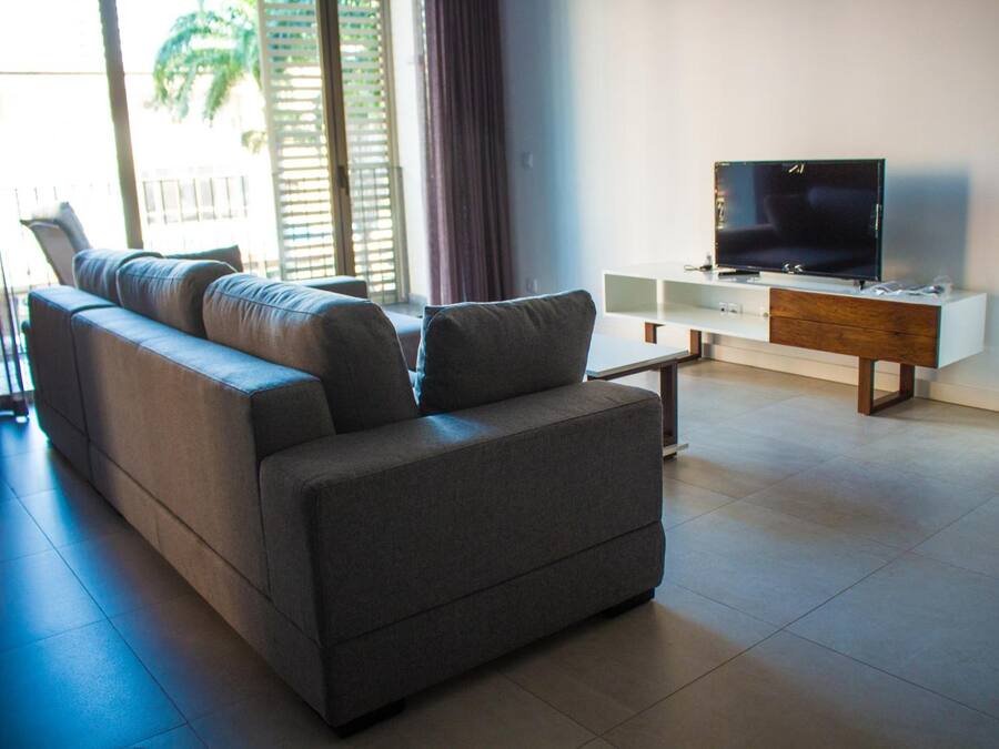 A modern living room with a grey sofa, a TV on a wooden stand, and a white console table.