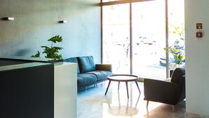 Un área de recepción moderna con mostrador, asientos y amplias ventanas que dejan entrar luz natural.