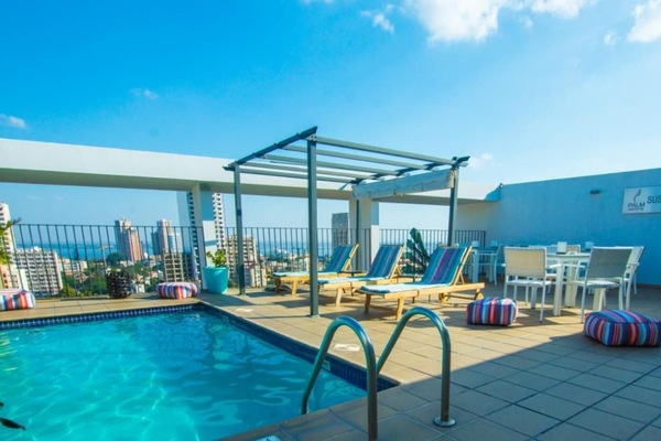 Una piscina al aire libre, sombrillas, sillones reclinables de piscina