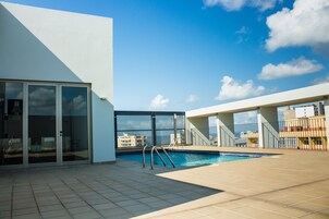 Una piscina al aire libre, sombrillas, sillones reclinables de piscina