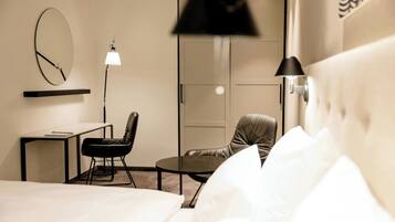 Ein Hotelzimmer mit einem Bett, einem Schreibtisch, zwei Stühlen, einem runden Tisch, einer Lampe und einem Kleiderschrank.