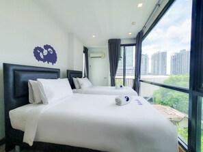 A hotel room with two beds, a large window with a city view, and a decorative wall piece. - Kokotel Bangkok Sukhumvit 50 (Bangkok)