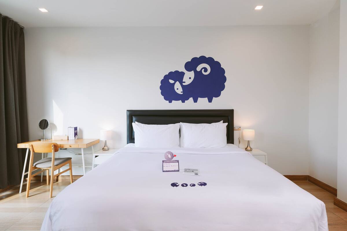 Une chambre d’hôtel comprenant un lit, un bureau, une chaise et un élément de décoration murale.