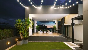 An outdoor seating area with modern design, featuring a flat roof and a view of the sunset. - Kokotel Bangkok Sukhumvit 50 (Bangkok)