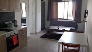 A compact living space with a kitchenette, a dining area, and a bed. - Mylos Court Apartments (Limassol)