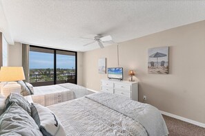 A hotel room with two beds, a ceiling fan, a TV, and artwork on the walls. - Anchorage Resort Top Floor 2 Bedroom Condo with Gulf Views (Siesta Key)