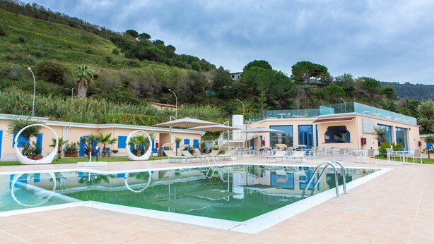 A pool area with lounge chairs and a building with blue accents. - Galìa Luxury Resort (Pizzo)