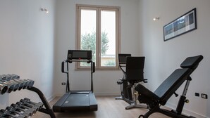 A gym with a treadmill, elliptical, bench press, and dumbbells. - Galìa Luxury Resort (Pizzo)