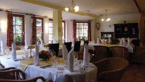A dining area with tables set for a meal, featuring white tablecloths, napkins, and cutlery. - Hotel und Restaurant Landhaus Hönow oHG (Hoppegarten)