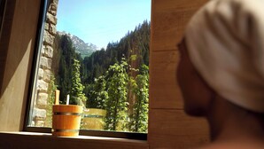 A window with a view of a mountainous landscape, a wooden bucket, and a stone wall. - Arlberg Resort Klösterle (Klösterle am Arlberg)
