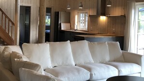 A spacious room with a wooden interior, a sofa set, a dining table, and a staircase. - Stylish Lake house, outdoor hottub Lake view Close to nature. Pet friendly. (Våxtorp)