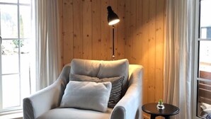 A modern room with a beige armchair, a small round table, and a floor lamp. - Stylish Lake house, outdoor hottub Lake view Close to nature. Pet friendly. (Våxtorp)
