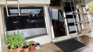 A boat's interior with a steering wheel, control panel, and a ladder.