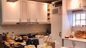 Cozinha com armários brancos, bancada de madeira e diversos alimentos.