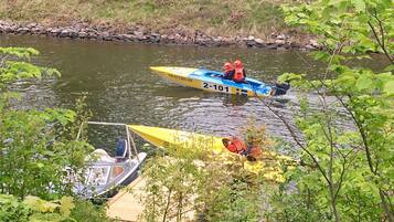 Twee boten op een rivier, één met een blauw-geel kleurenschema en de andere geel, beide met mensen die een reddingsvest dragen.