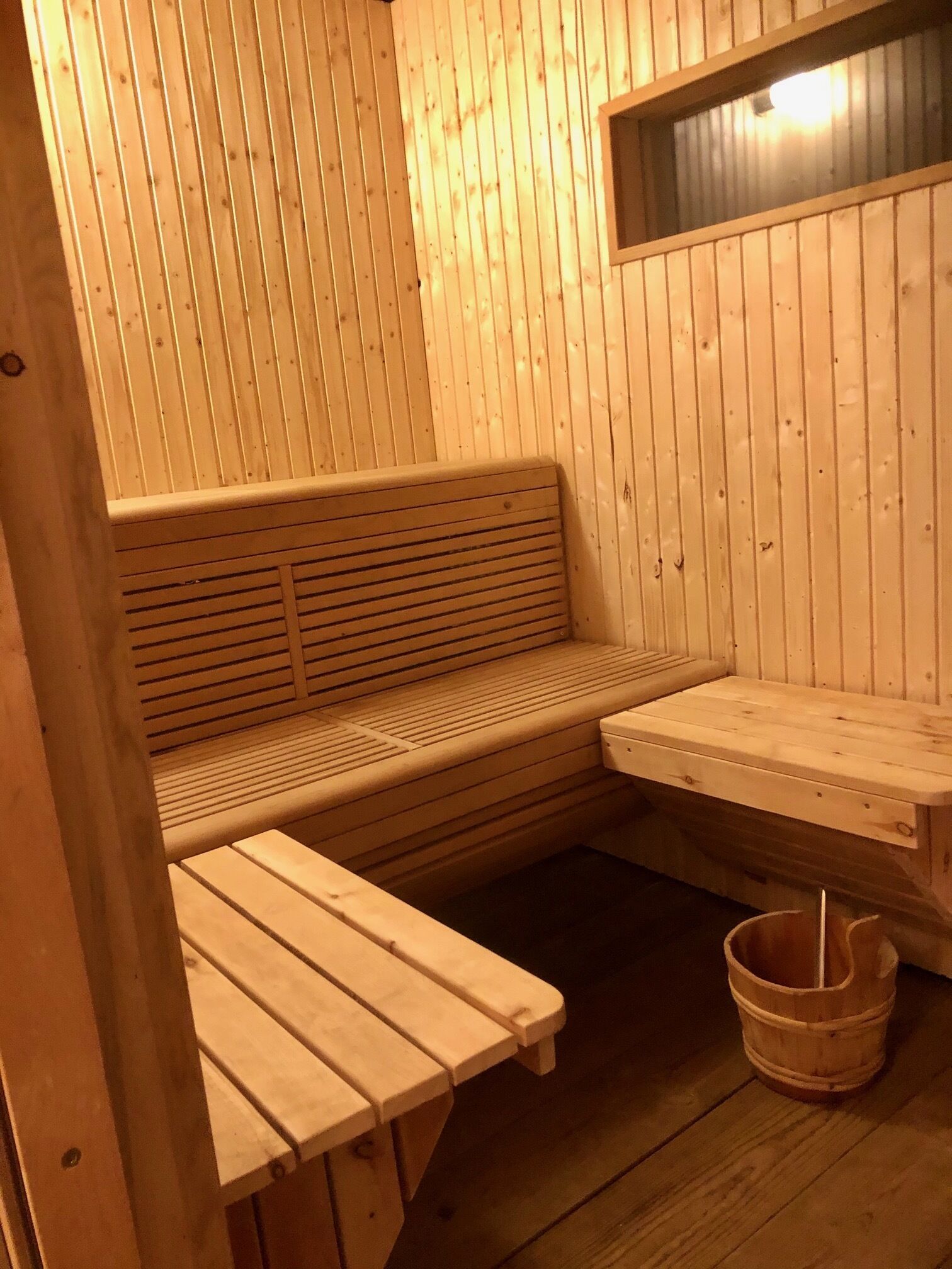 Una sauna de madera con un banco y una pequeña mesa.