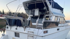 Um iate branco chamado 'Elvira' atracado em um porto com área de convés coberta, uma cabine pequena e uma prancha de wakeboard.