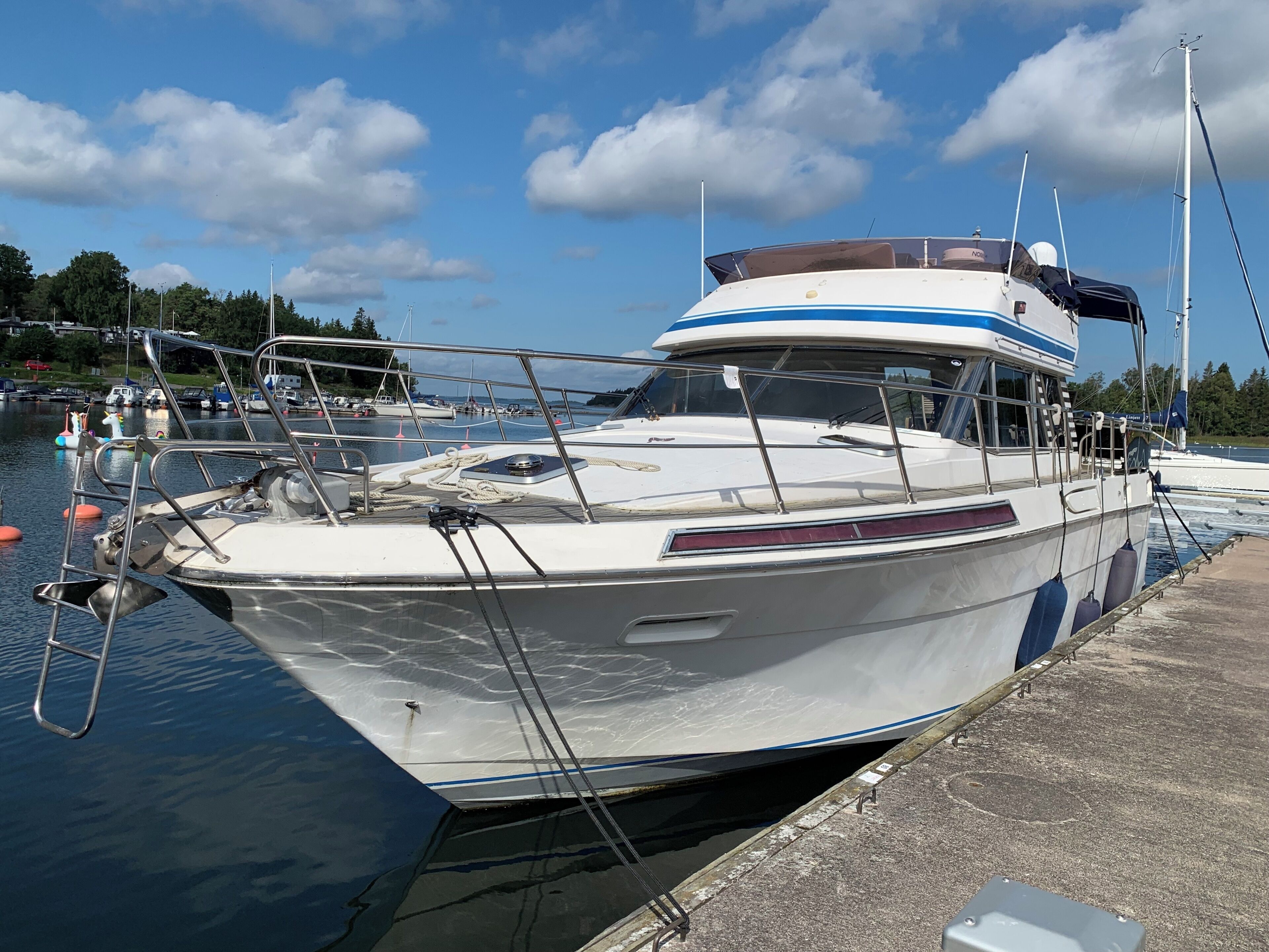 A white boat docked at a marina with a clear sky and calm water.