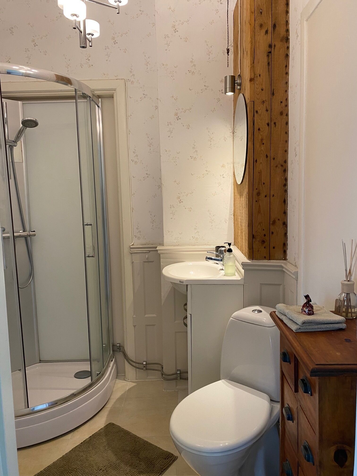 A bathroom with a glass-enclosed shower, a white sink, and a toilet.