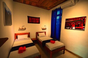 A room with two single beds, a small table, and a wall-mounted air conditioner. - World BnB (Labuan Bajo)