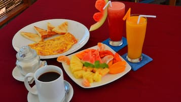 A breakfast setting with toast, omelette, fruit, coffee, and two drinks on a red table.