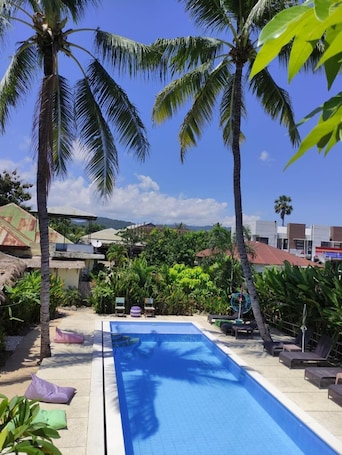 Una piscina al aire libre, sombrillas, sillones reclinables de piscina
