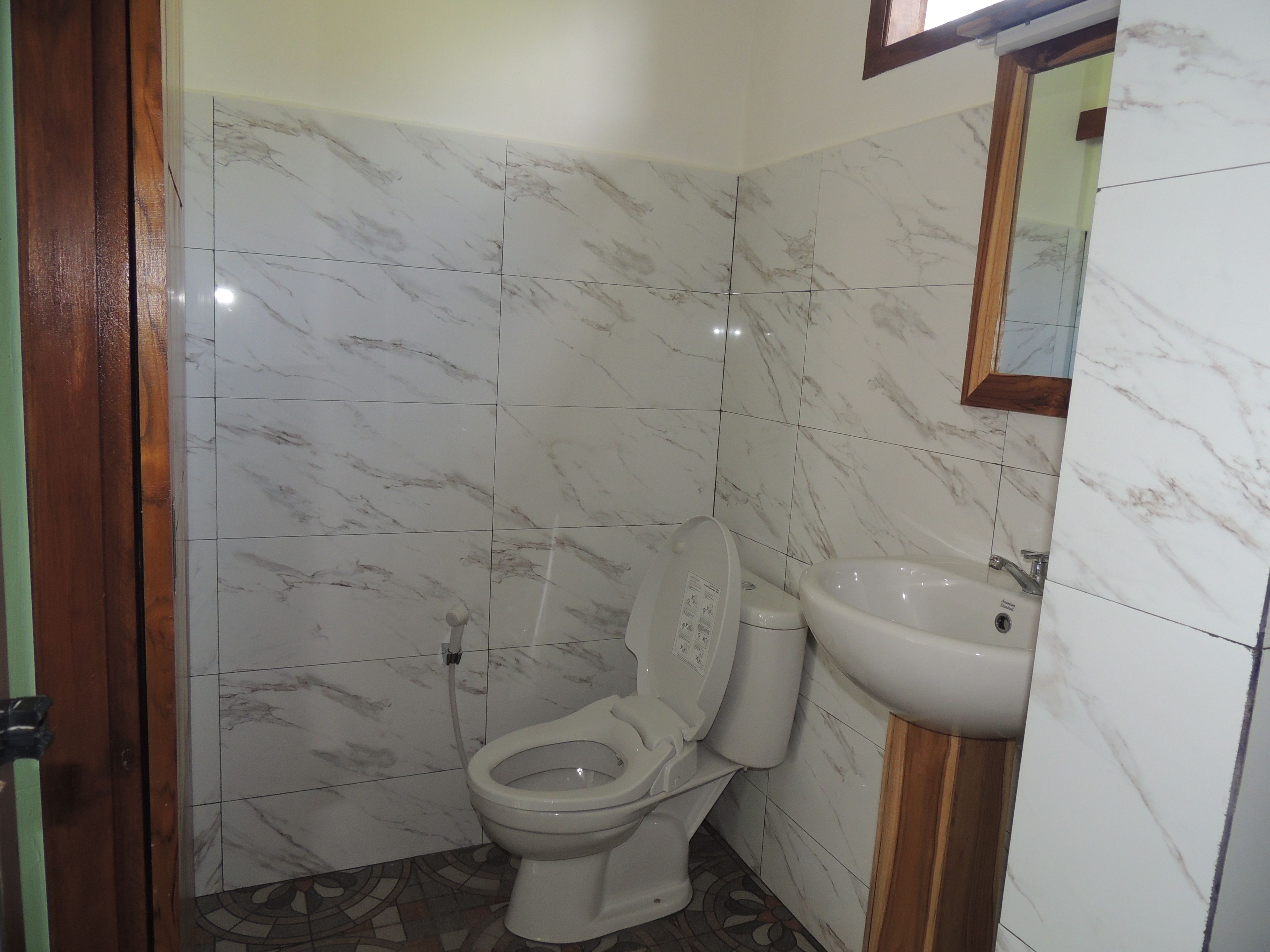 A bathroom with a toilet, sink, and mirror.