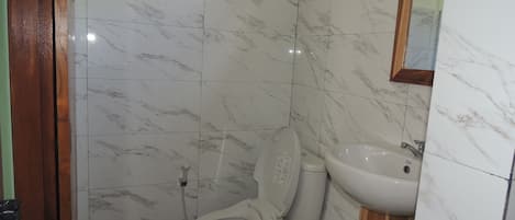 A bathroom with a toilet, sink, and mirror.