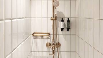 Une douche avec un plafond en bois, des murs recouverts de carreaux blancs et une pomme de douche à main.