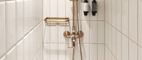 Una ducha con techo de madera, paredes con azulejos blancos y un cabezal de ducha de mano.