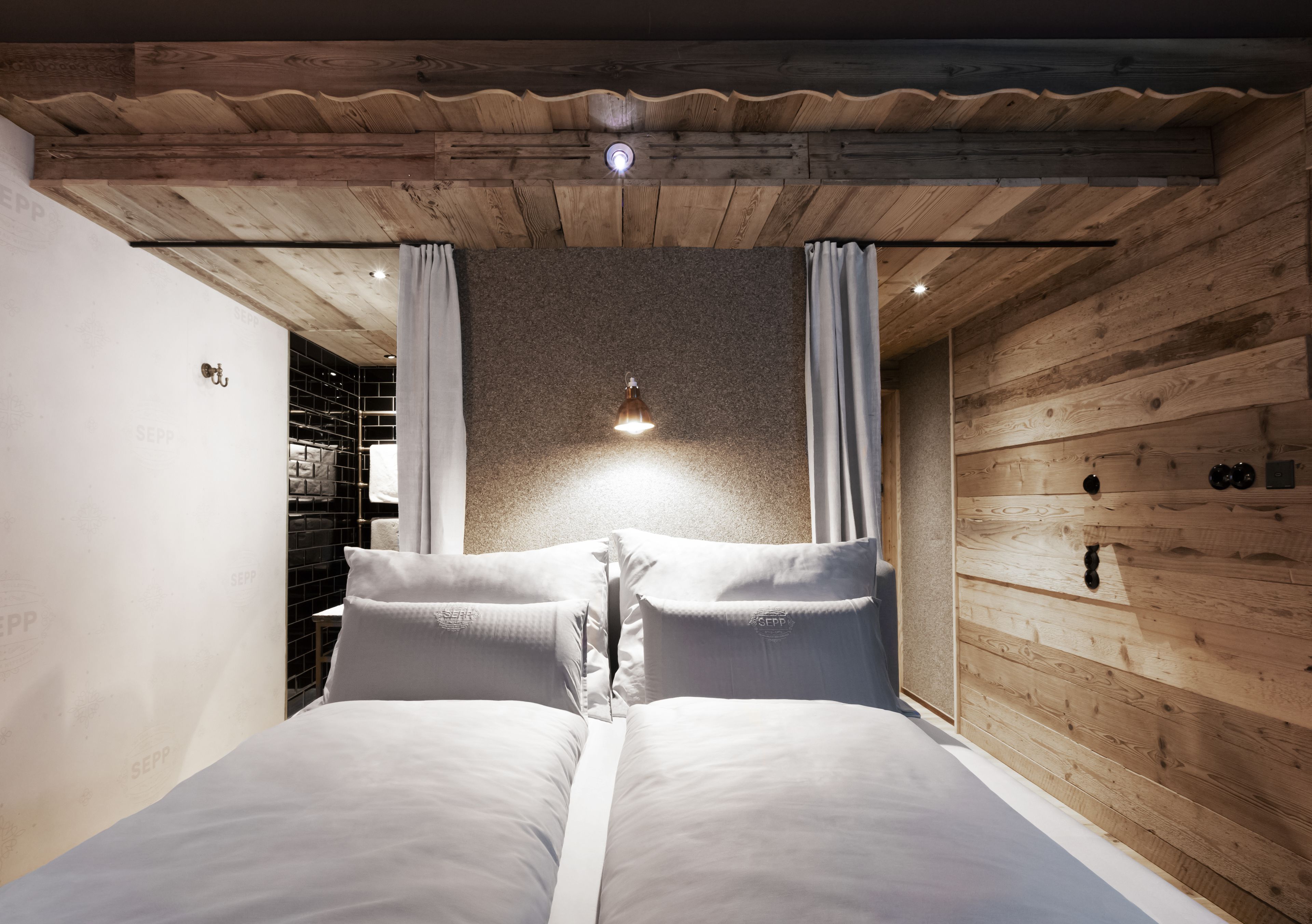 Ein Schlafzimmer mit Holzboden, einem Bett mit weißer Bettwäsche und einem kleinen Regal mit Handtüchern.
