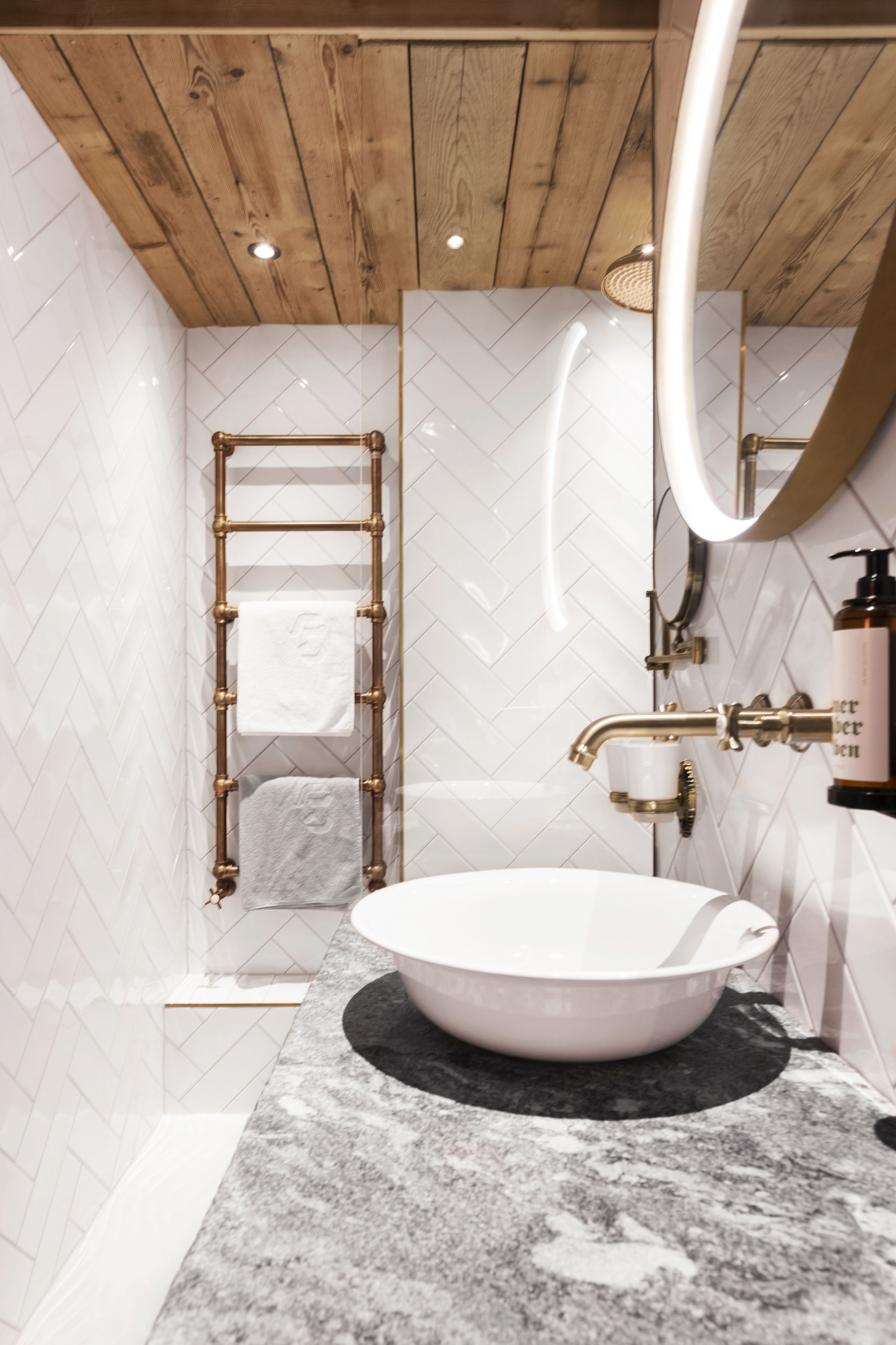 A modern bathroom with a freestanding bathtub, a wooden ceiling, and a marble countertop.