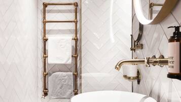 A modern bathroom with a freestanding bathtub, a wooden ceiling, and a marble countertop.