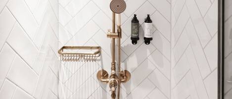A shower with a wooden ceiling, white herringbone-patterned walls, and a gold showerhead.