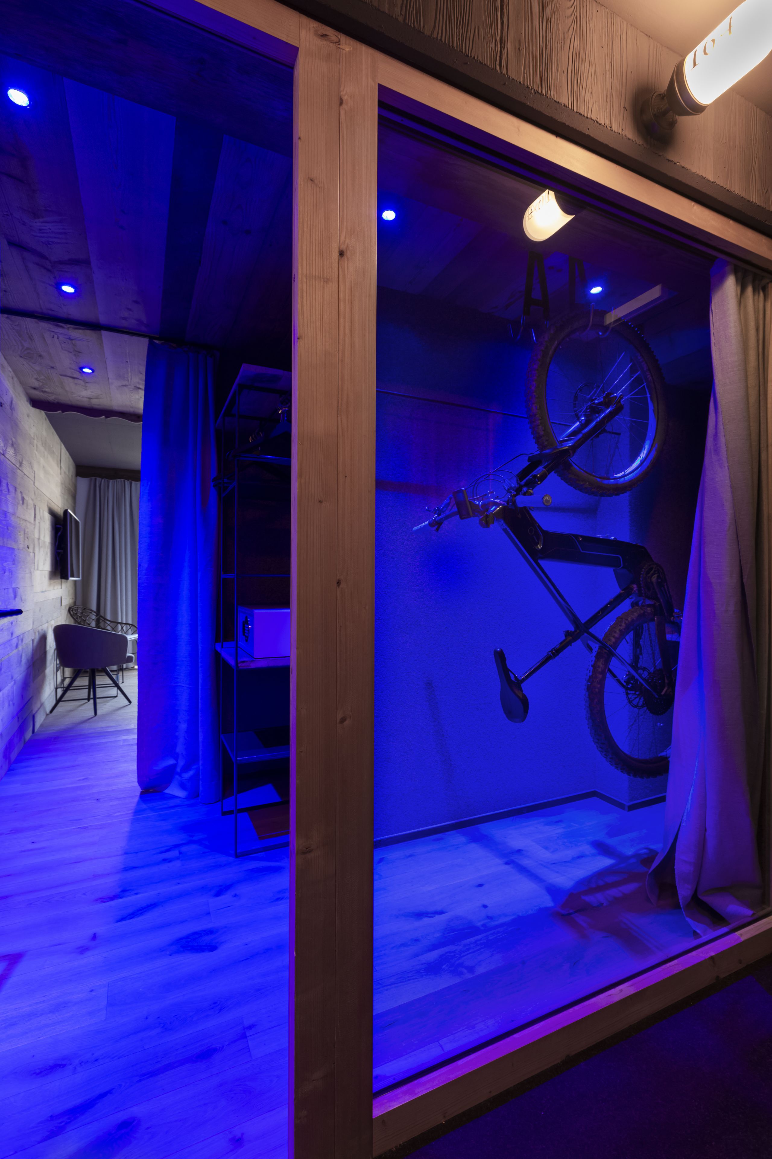 Ein Zimmer mit Holzbalkendecke, einem an der Wand befestigten Fahrrad und einem Fenster mit Vorhängen.