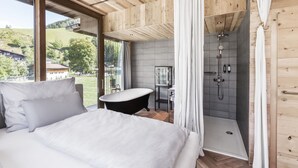 A bedroom with a large bed, a vanity, and a shower. - SEPP - Alpine Boutique Hotel (Maria Alm am Steinernen Meer)