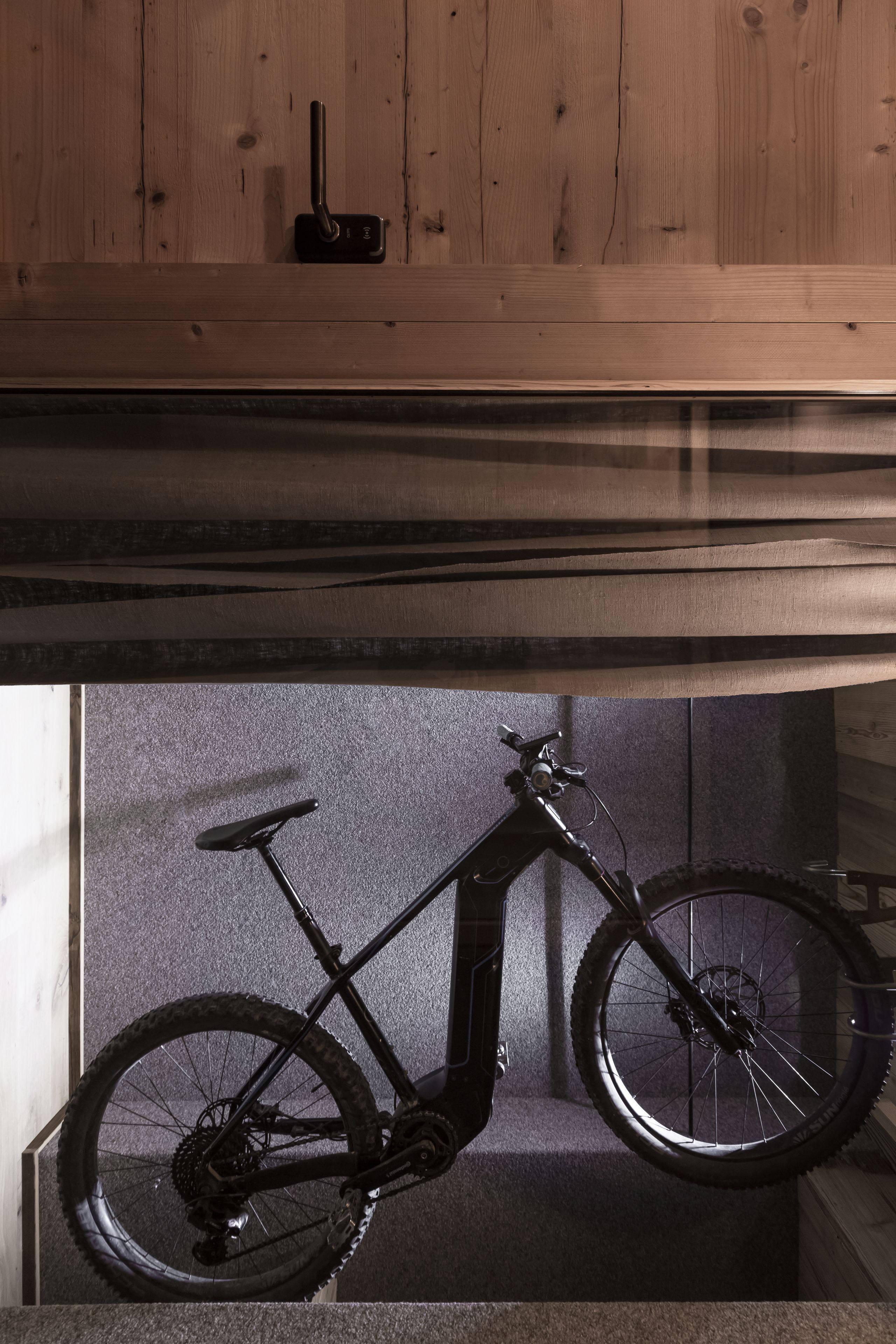 A bicycle mounted on a wall with a wooden panel above.
