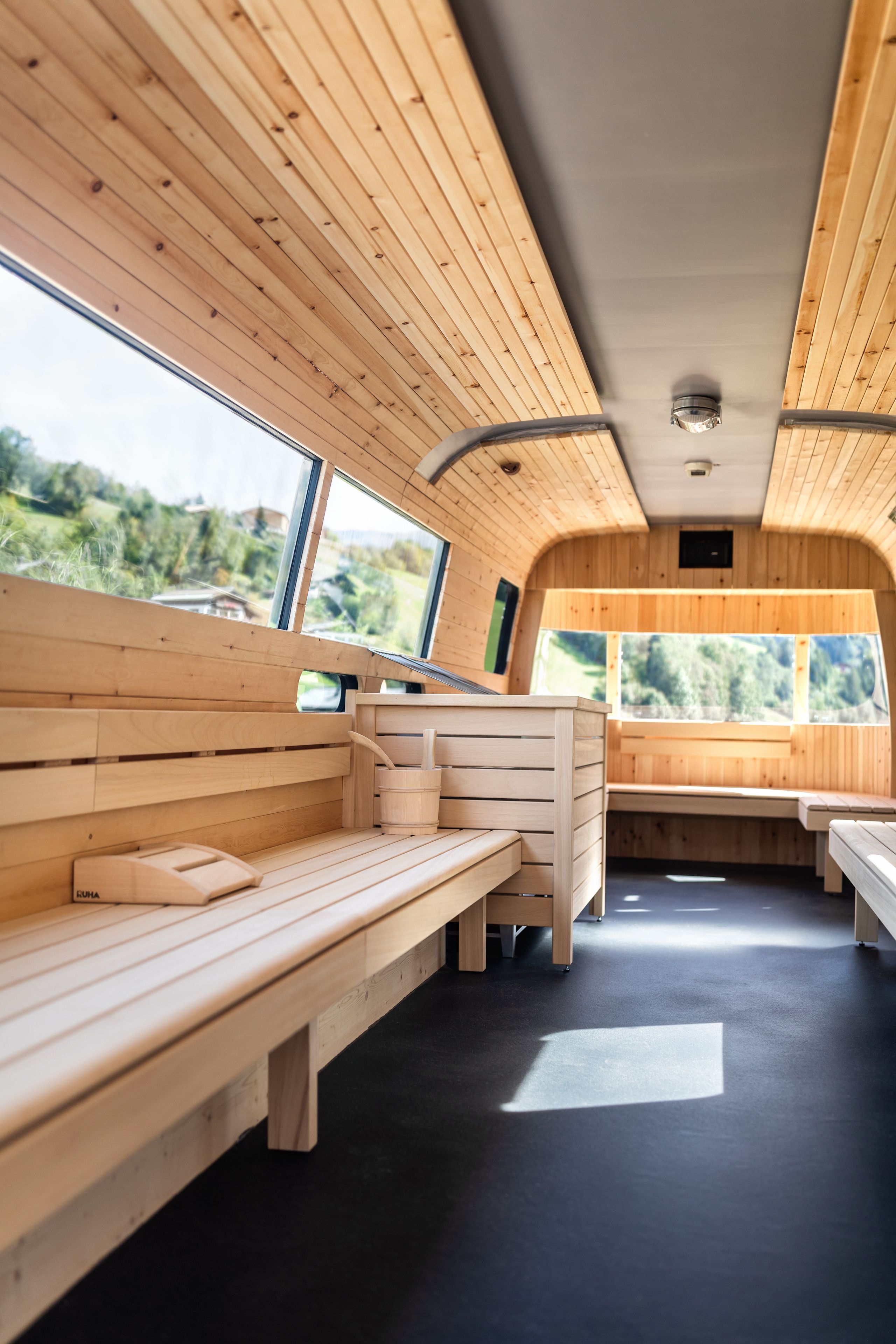 A cabin with wooden benches, a small table, and a window offering a view of the outdoors.