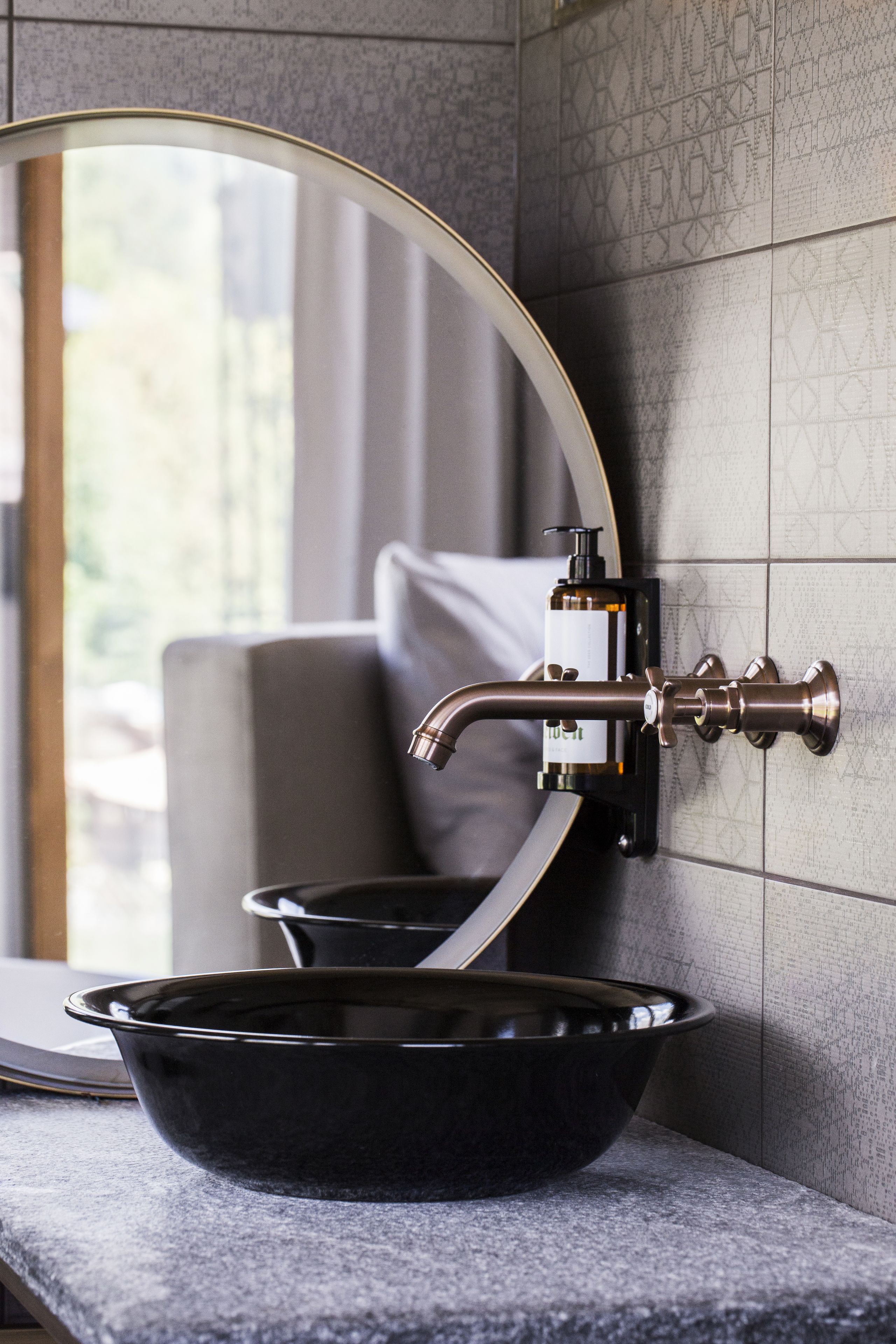 Une salle de bain avec un lavabo noir, un robinet mural et un miroir.