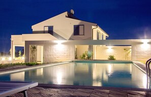 Una casa moderna con piscina, destacando un diseño minimalista y un techo plano.