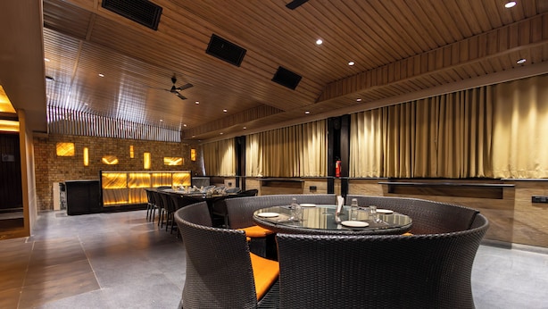 A modern interior with a bar area, wicker furniture, and a ceiling with recessed lighting. - Kyriad Hotel Indore (Indore)