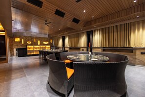 Ein modernes Interieur mit Barbereich, Korbmöbeln und einer Decke mit eingelassener Beleuchtung.