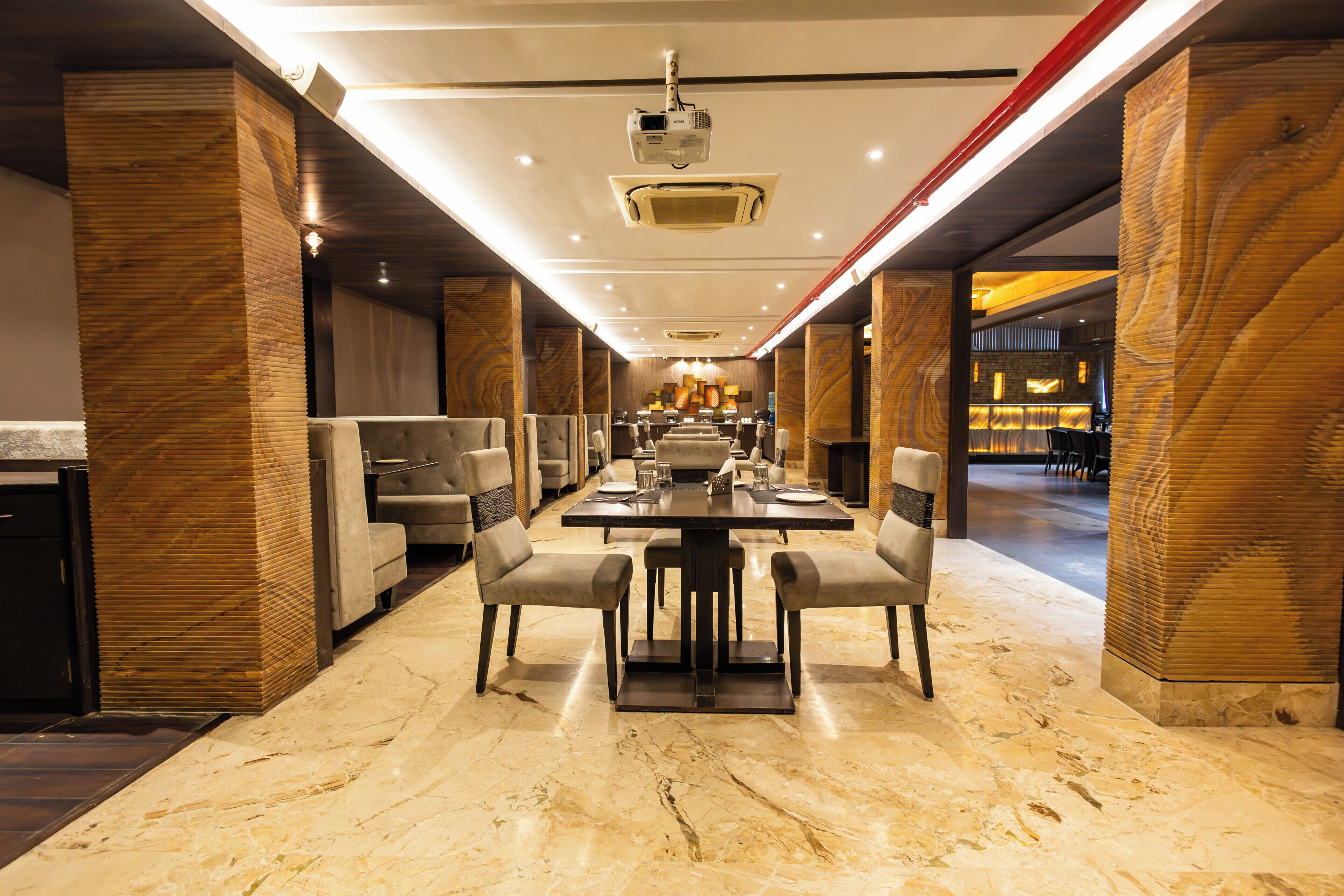 A spacious dining area with a long table, multiple chairs, and a ceiling projector.